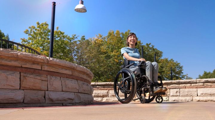 Wheelchair user with Empulse M90 power assist outdoors in the sunshine