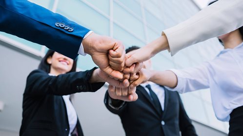 A group of employees reaching their hands out together.